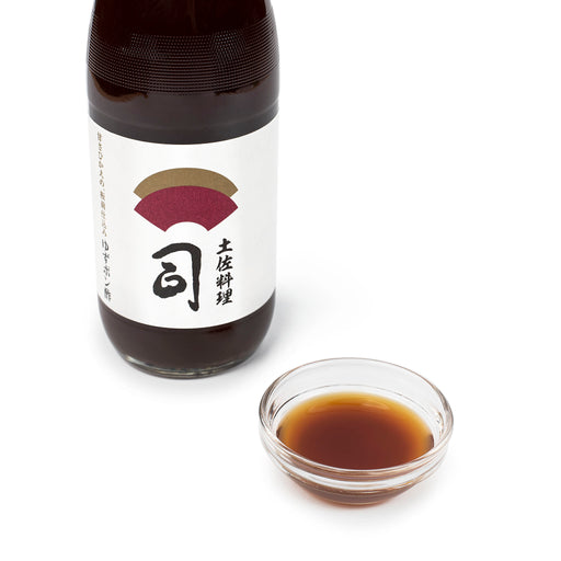 A bowl of ponzu sauce next to a botte of the product