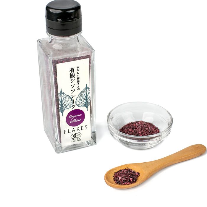 A spoon of and a small bowl of organic shiso furikake next to bottle of the product