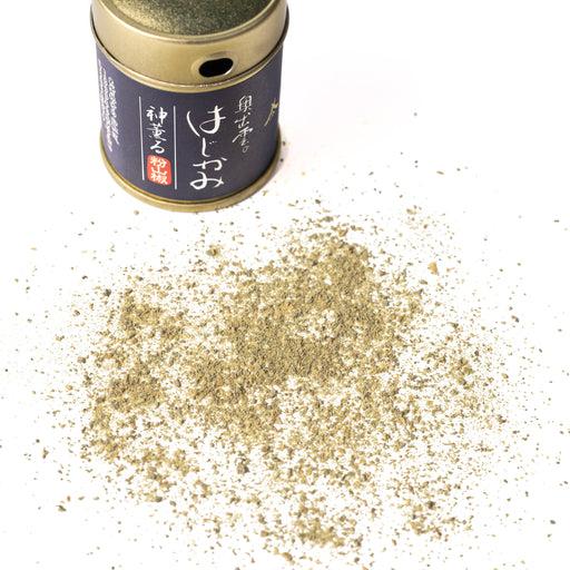 Scattered sansho pepper powder next to package bottle of the product