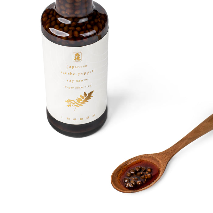 A wooden spoon of sansho pepper soy sauce next to bottle of the product