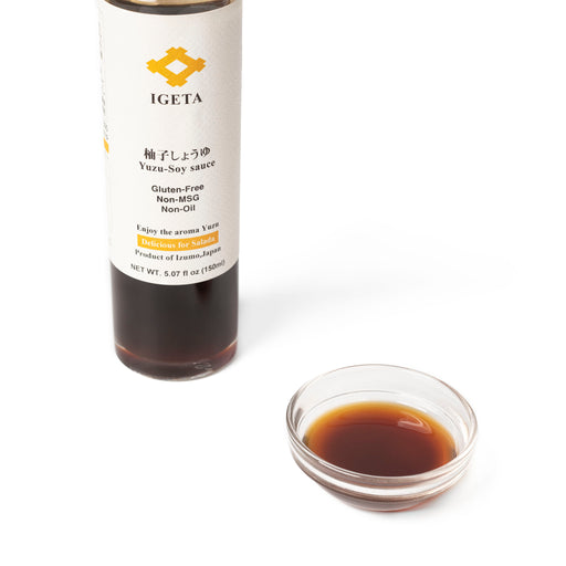 A glass bowl of yuzu infused tamari soy sauce next to bottle of the product