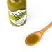 A wooden spoon of yuzu hot sauce next to package bottle of the product