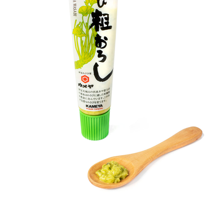A wooden spoon of coarsely grated hon wasabi next to package bottle of the product