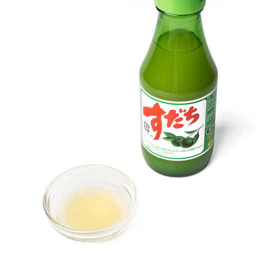 A bowl of sudachi juice next to a bottle of the product