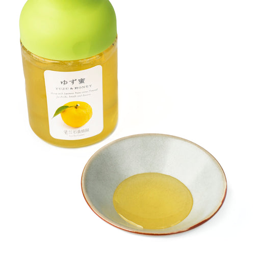 A small bowl of Yuzu Honey next to package bottle of the product