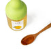 A wooden spoon of Yuzu Honey next to package bottle of the product