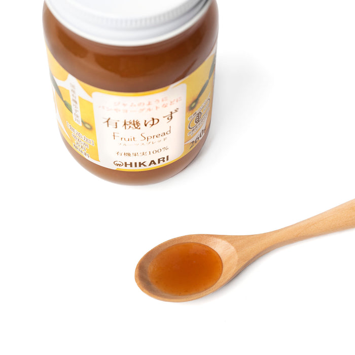 A spoon of organic yuzu spread next to bottle of the product