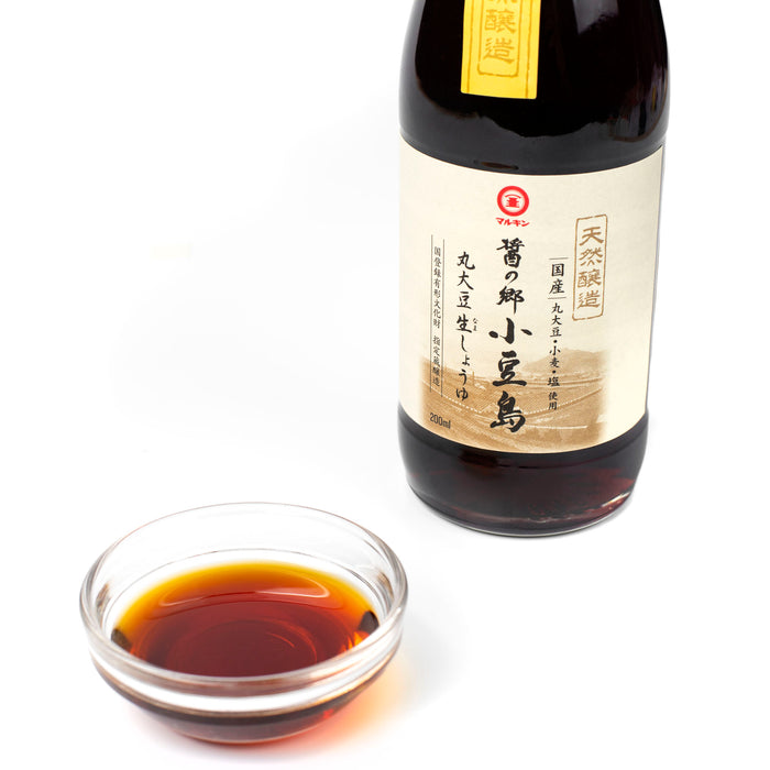 A small bowl of soy sauce next to bottle of the product