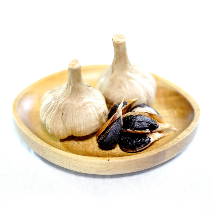 A bowl of two black garlic bulbs and five cloves