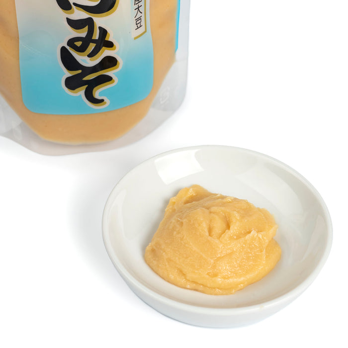 A small bowl of white miso next to package of the product - diagonal angle