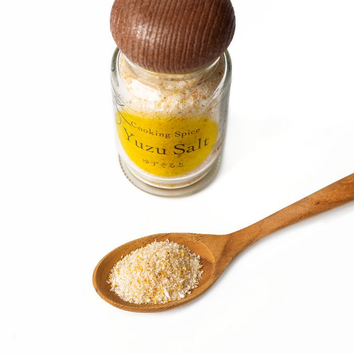 A wooden spoon of yuzu salt next to bottle of the product