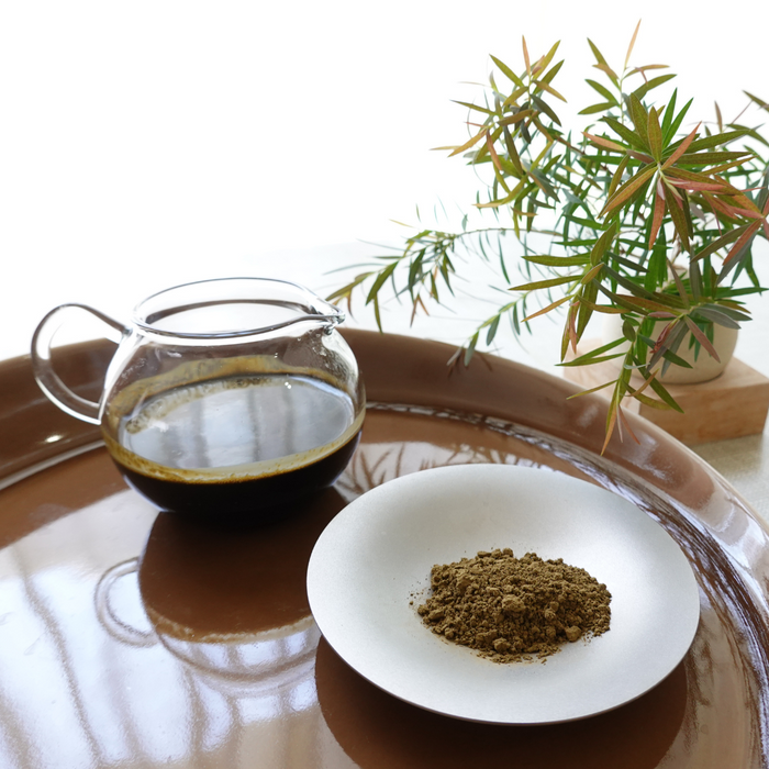 A plate of hojicha powder next to a pot of hojicha tea