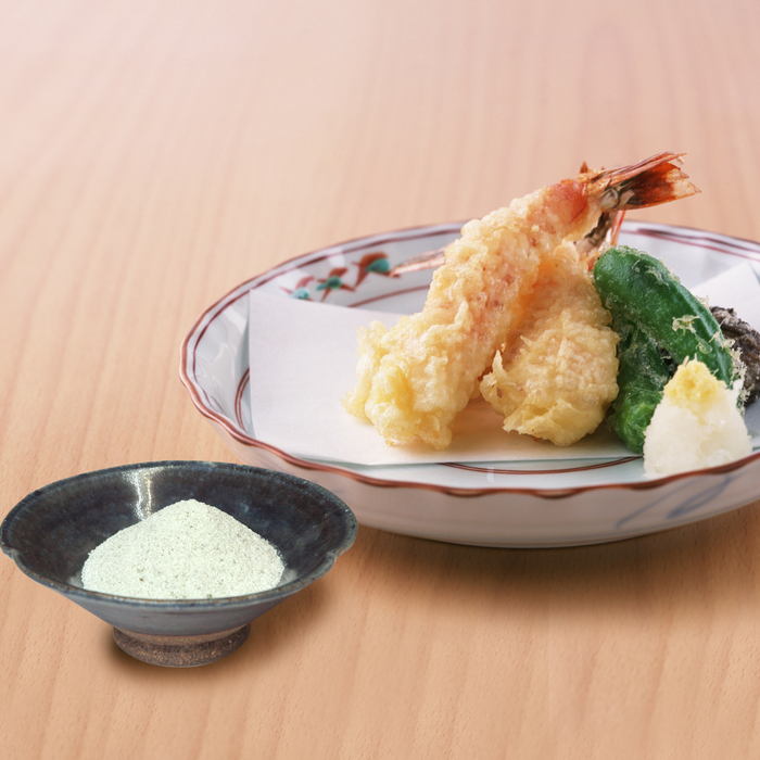 A bowl of wasabi salt next to tempura shrimps