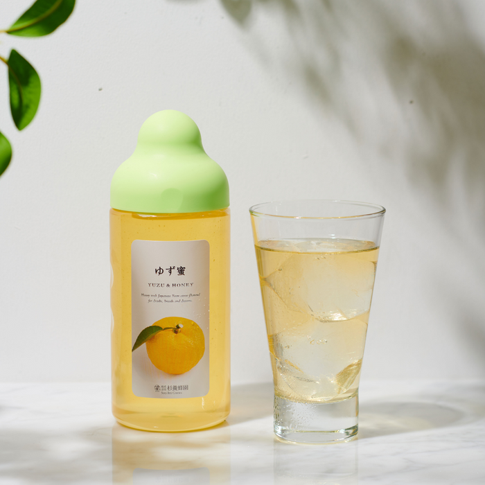 A glass of yuzu blended soda next to package bottle of the product