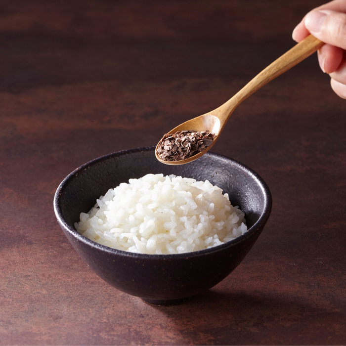 Man pouring furikake onto steamed rice