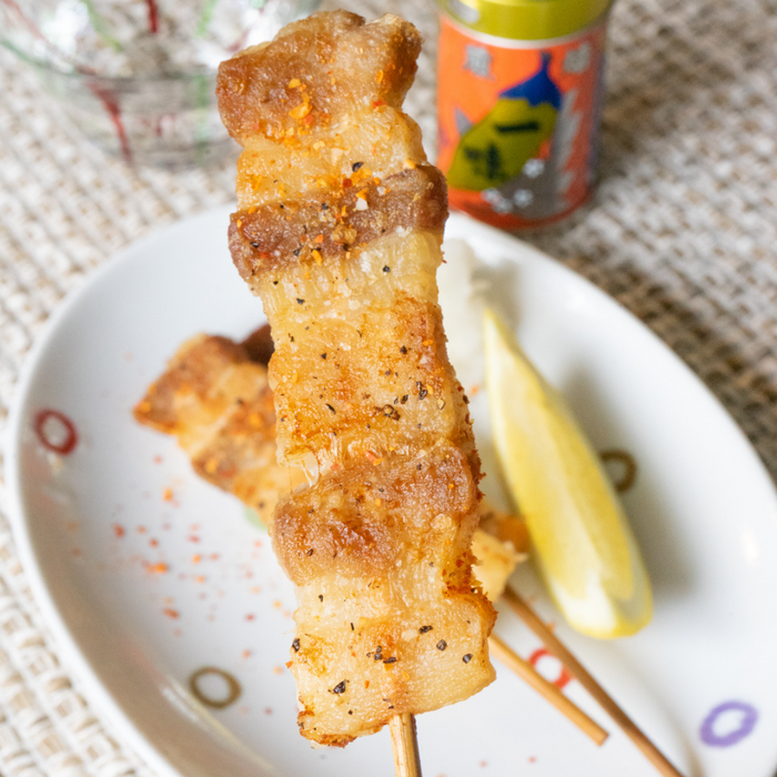 Close up angle of chicken skewer topped with ichimi pepper