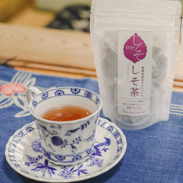 A cup of shiso tea next to package bag of the product