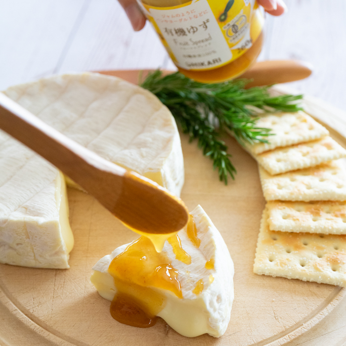 Man pouring organic yuzu spread onto a slice of cheese