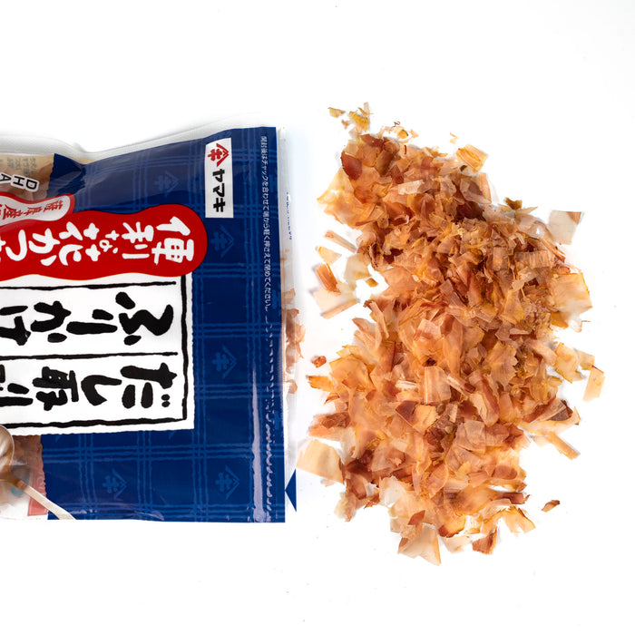 Overhead angle of scattered dried bonito flakes popping out of package of the product