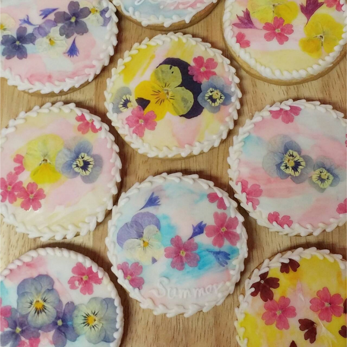 Nine pieces of round shaped icing cookies topped with many kinds of dried edible flowers
