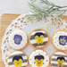 Six pieces of round shaped icing cookies topped with dried edible flowers