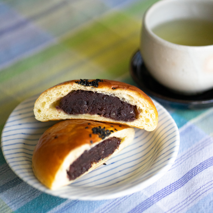 Red bean stuffed bread on a plate next to a cup of tea
