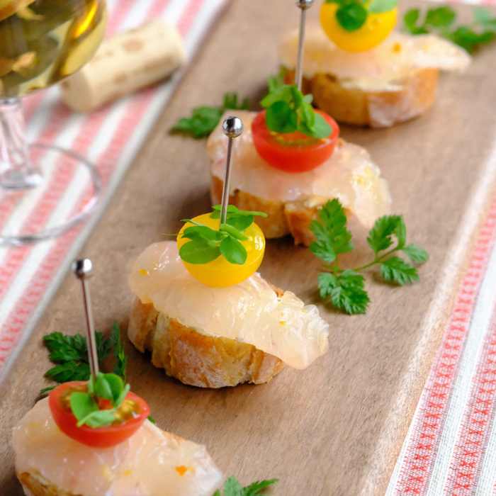 A plate of bruschetta topped with fish and tomatoes
