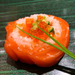 A salmon wrapped sushi topped with salmon roe