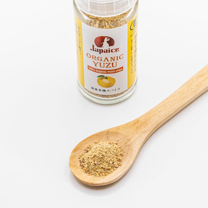 A spoon of organic yuzu powder next to a bottle of the product
