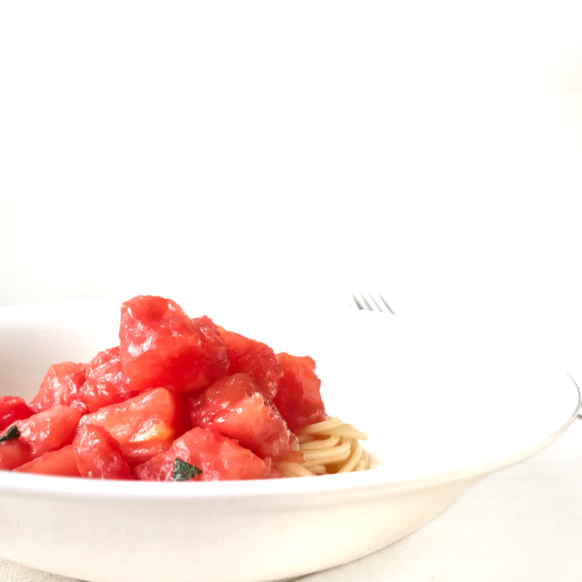 A plate of spaghetti topped with diced tomatoes