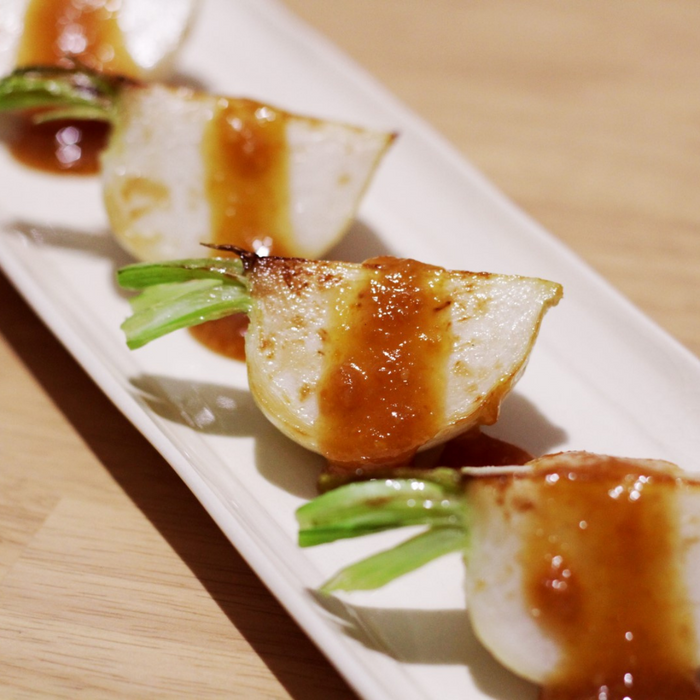 A plate of grilled radish sliced into four pieces and topped with organic yuzu spread