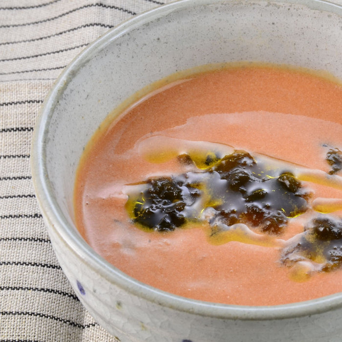 A bowl of creamy tomato soup topped with nori seaweed paste