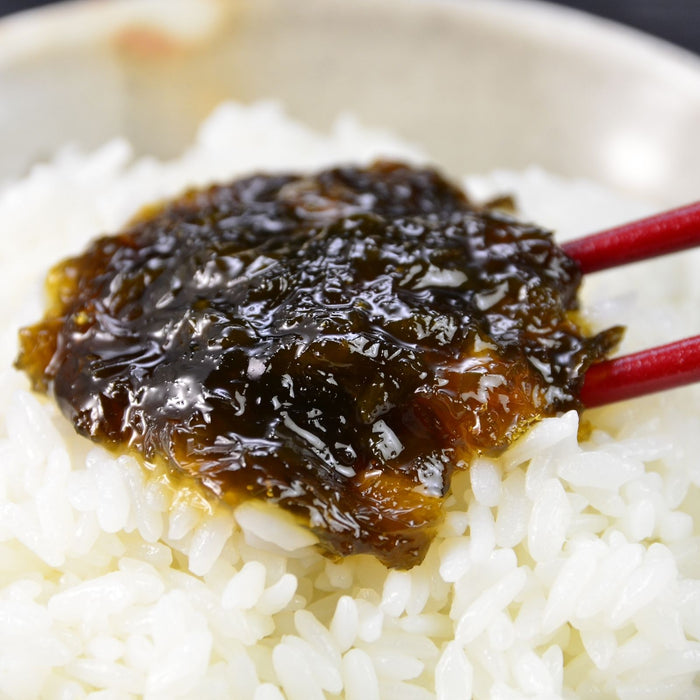 Man taking steamed white rice topped with nori seaweed paste with chopsticks