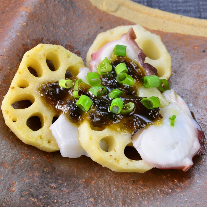 A plate of sliced lotus root and octopus topped with nori seaweed paste and scallion