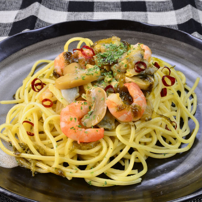 A plate of spaghetti topped with shrimps, mushrooms, and nori seaweed paste