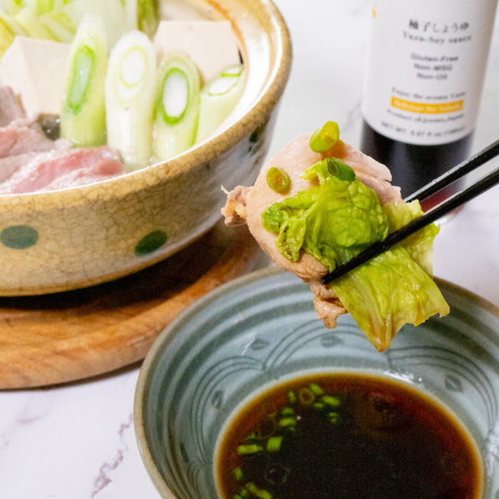 Man taking dipping simmered pork into yuzu-infused soy sauce