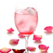 A glass of rose soda surrounded by rose petals