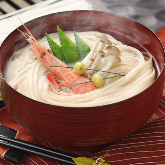 A bowl of udon noodles soup with shrimp and mushrooms