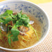 A bowl of kabocha blended shirataki noodles soup topped with clams and herbs