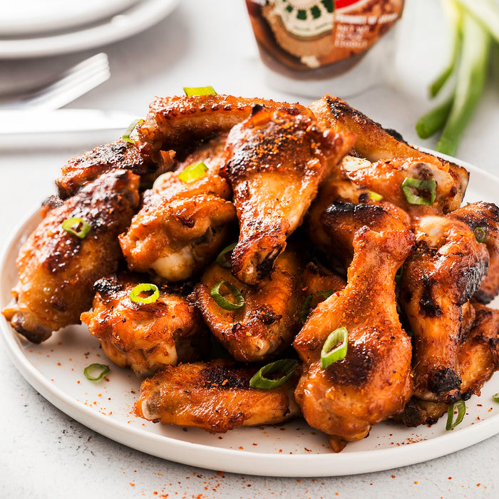 A plate of grilled chicken wings topped with scallions