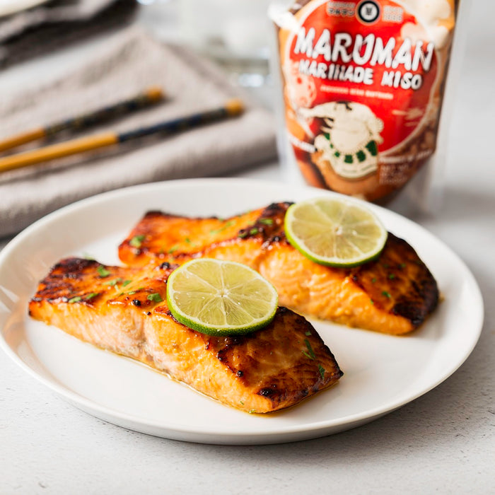 A plate of two pieces of grilled salmon topped with slices of lime