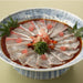 A plate of sliced white fish sashimi soaked with ponzu sauce